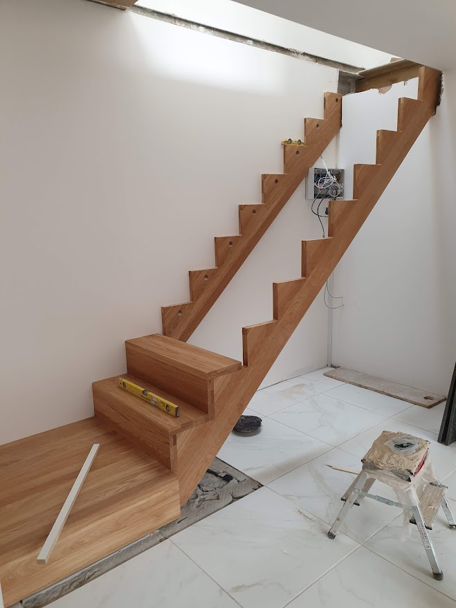 Solid oak staircase installation manufactured abroad from 40mm thick real wood by Optima Builders in West Hampstead new build project
