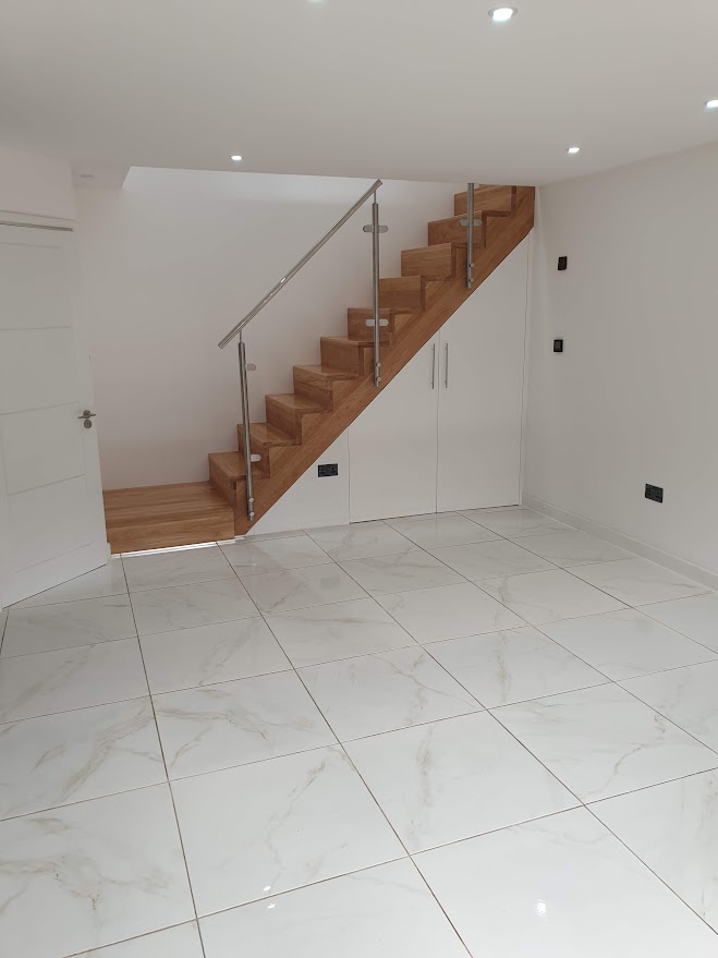 Bespoke staircase manufactured in Poland, sprayed like a car, with glass balustrade – new build project in West Hampstead by Optima Builders