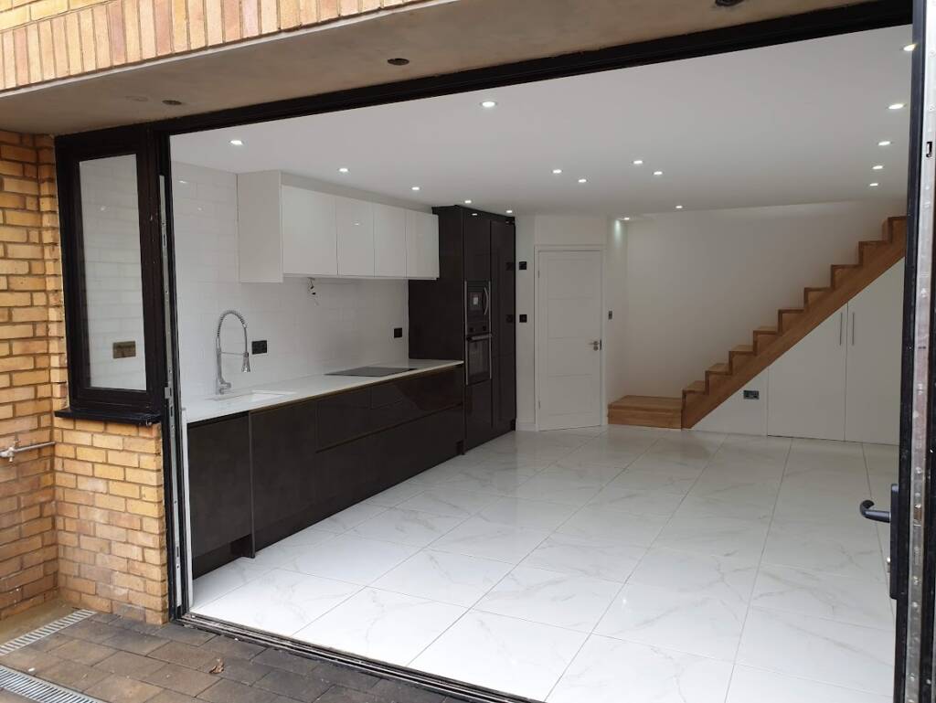 New build project in Mill Lane, West Hampstead – kitchen installation, porcelain flooring with underfloor heating, oak staircase, and modern utility cupboard by Optima Builders