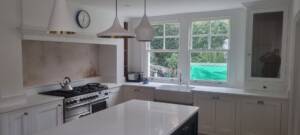 Designer pendant lights above kitchen island with display cabinet and bespoke storage – Muswell Hill N10 renovation.